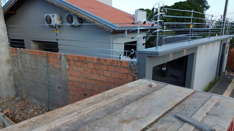 Residência com cerca elétrica e concertina reta instaladas sobre o muro