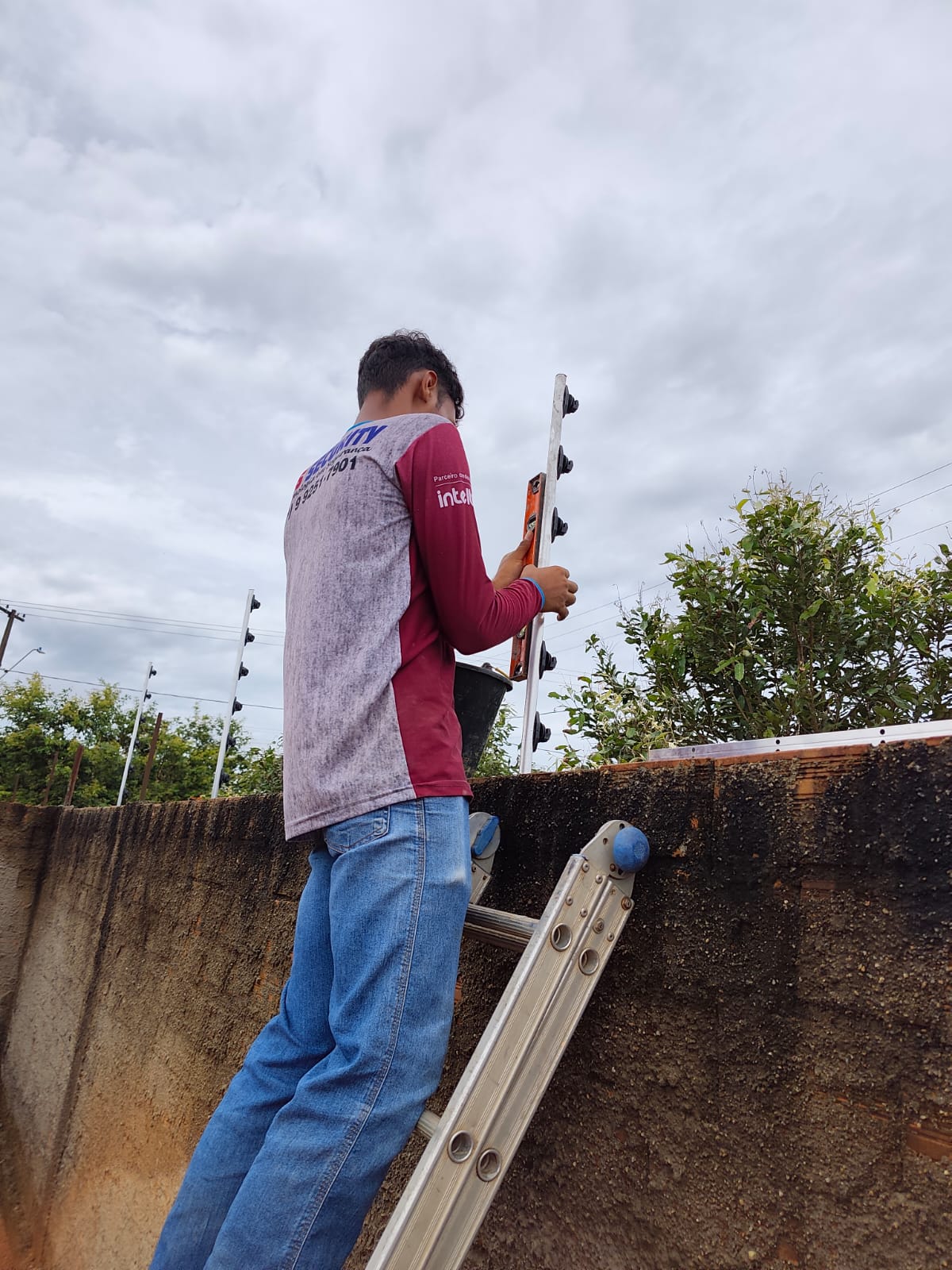 Técnico da LS Security fixando haste de cerca elétrica no muro com nível