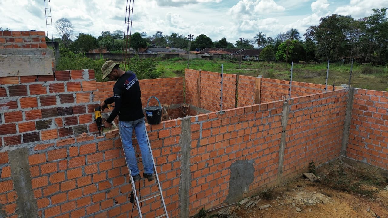 Técnico furando muro para fixação de hastes de cerca elétrica